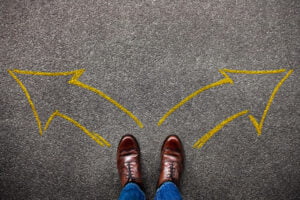 Image of yellow arrows drawn on the pavement at the feet of a person. Showing the type of decision that you may struggle with but online therapy can hep with. When meeting with an online therapist for online therapy for men you can embrace the present so decision making is easier.
