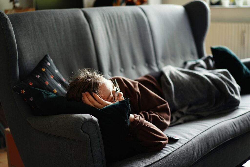 An image of man sleeping on a couch as a way to procrastinate the duties he is responsible for that day in California.