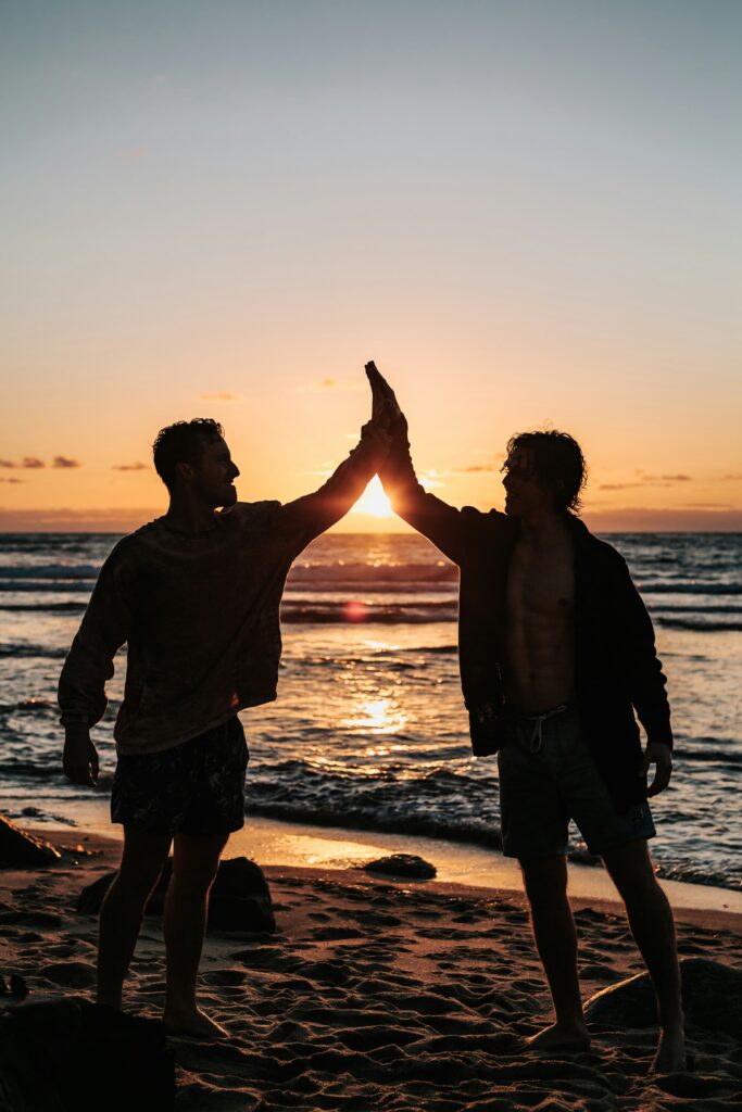 An image of two men standing on the beach with a sunset behind them giving a high five resembling the freedom they feel from therapy for anxiety and obsessive thinking in California