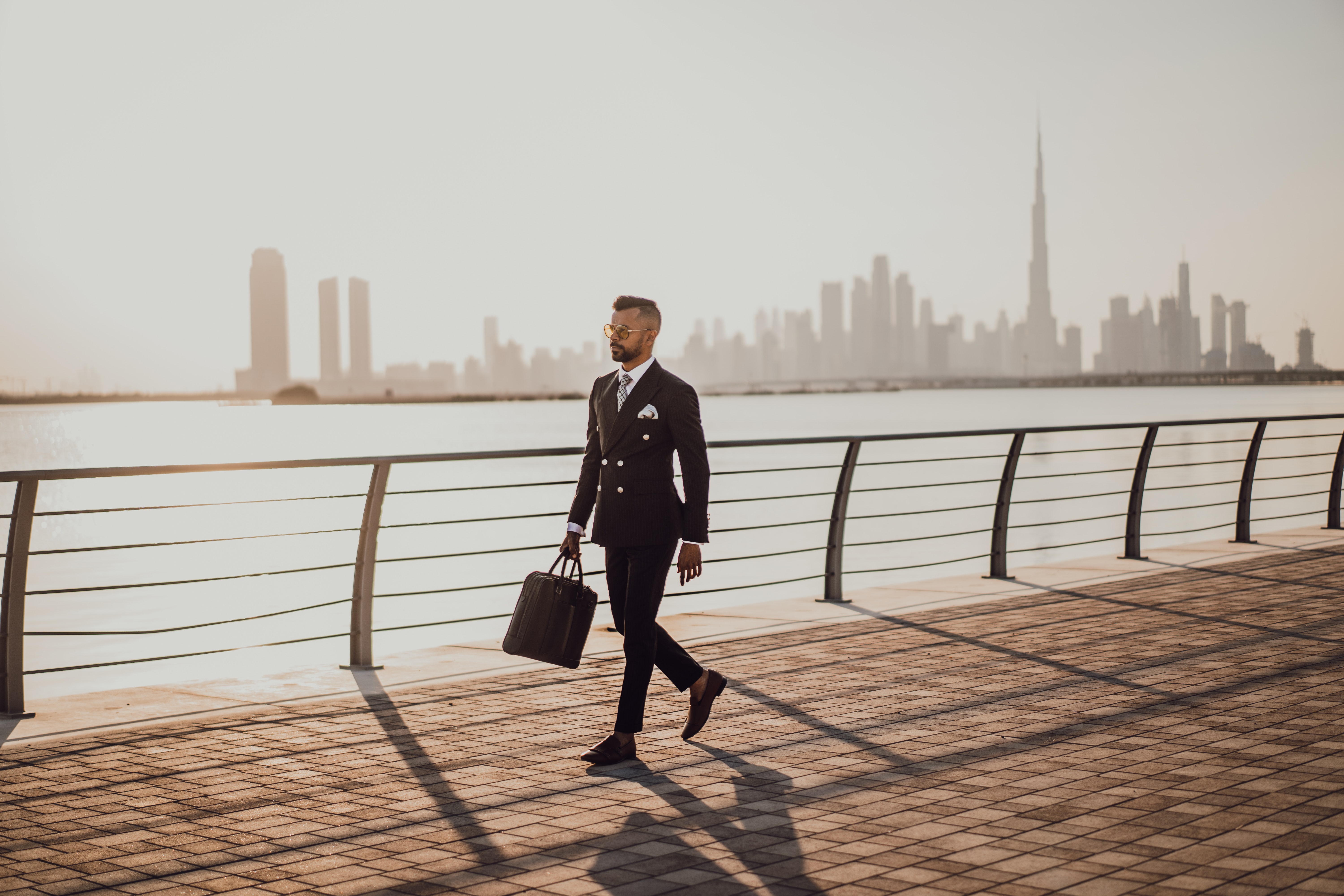 Image of a man walking holding a portfolio and he walks along a river. Showing how anyone can be suffering from Sunday night anxiety but there are ways to reduce stress and feel better. With the support of a San Diego therapist you can find balance in your life and begin to cope with stress. Learn tips now for stress management.