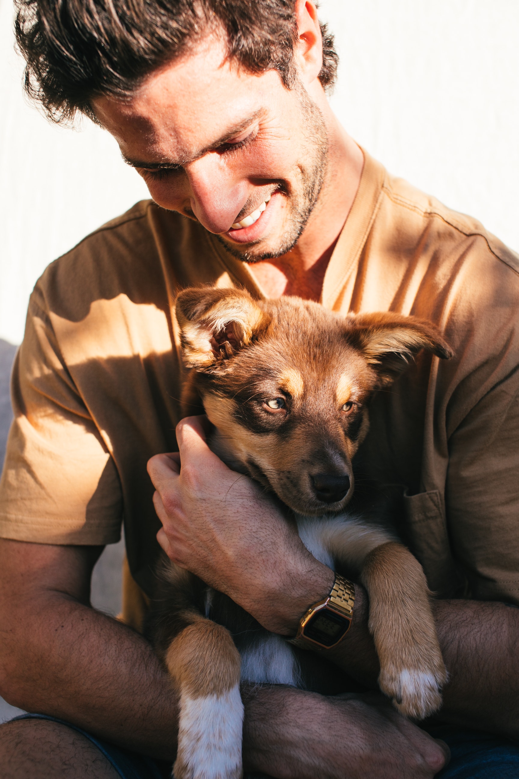Image of a man holding a puppy while smiling. Spending time with your pets is one way to reduce stress. In therapy for stress you will learn other tools for stress management in San Diego, CA.