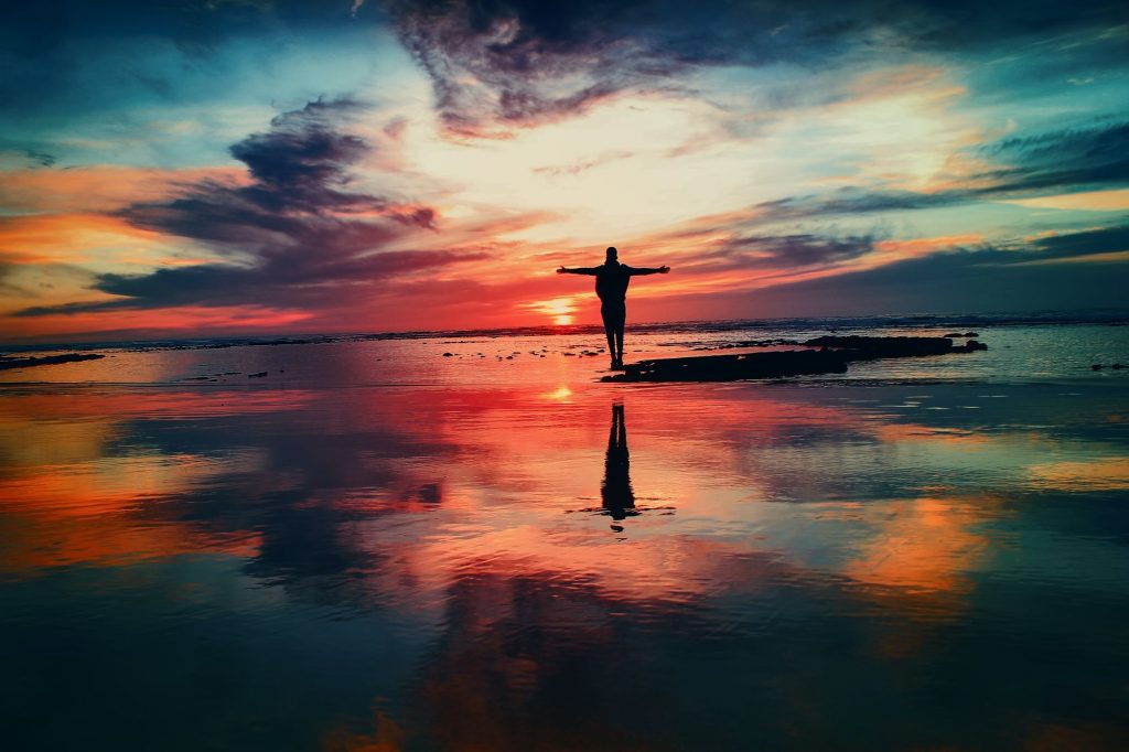 Image of a person standing with arms raised in a beautiful sunset after feeling relief from individual counseling in San Diego, CA. If you have been struggling you can feel this happy too with the support of individual therapy for adults in San Diego, California.