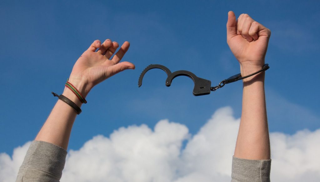 Image of two hands breaking out of handcuffs thanks to PTSD treatment in San Diego, CA. If your PTSD symptoms feel like handcuffs you can break free too with trauma therapy in San Diego, California.