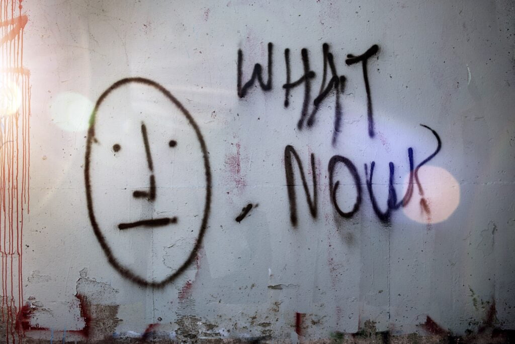 Image of graffiti that says "What now?" with a straight face next to it. If you are feeling stuck like this a San Diego trauma therapist can give you direction. Through PTSD treatment and trauma therapy you can heal and start moving forward with life so you do not feel like "what now?" anymore.
