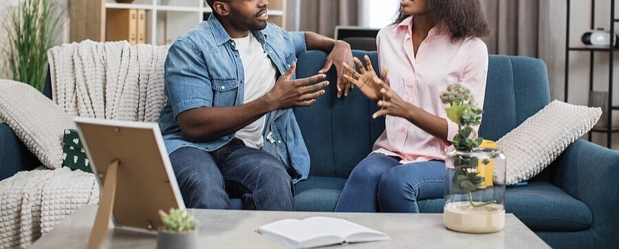 Image of a couple sitting on a couch facing each other talking. Showing one of the key techniques taught by couples therapists and marriage counselors in San Diego, CA. You can learn to communicate effectively like this in couples therapy.