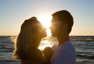 Image of a couple kissing in front of the ocean and a sunset. Representing the strength that can come in relationships after going to marriage counseling in San Diego with a marriage counselor.