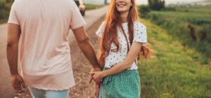 Image of a smiling woman looking backwards as she holds her partners hand. Showing the results that can come from online couples counseling with a San Diego couples therapist if you are ready to do the work.