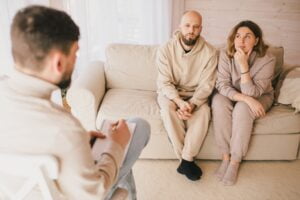 young couple sitting on the couch with a male therapist helping them understand what makes couples therapy successful?