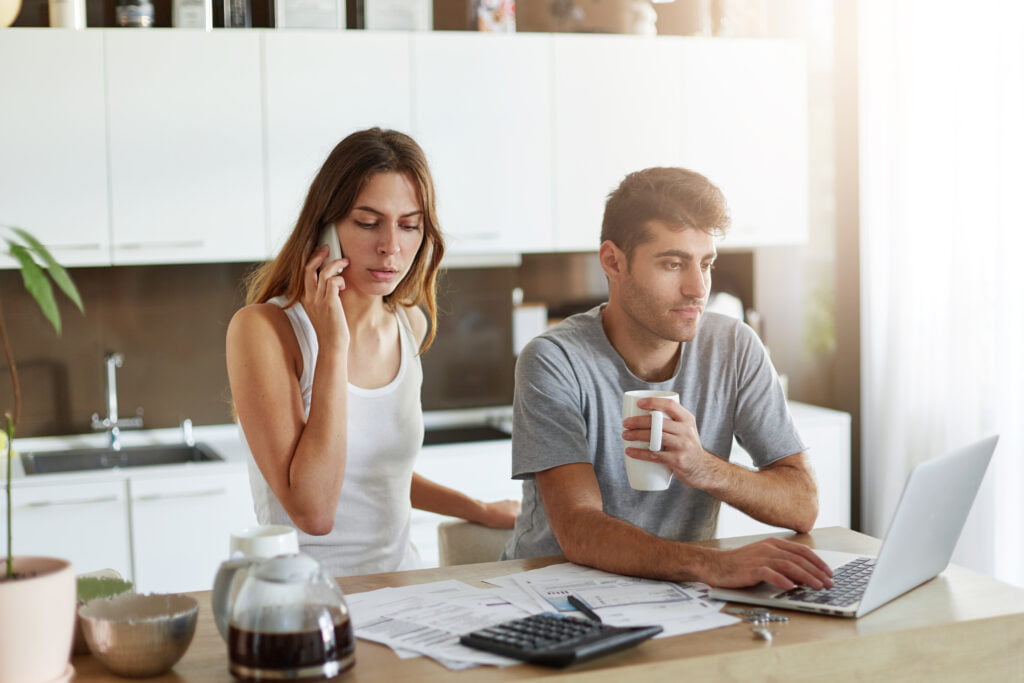 A young couple is working on tackling life responsibilities together such as bills, which can lead to getting stuck in the roommate phase of the relationship if they do not change up their routine.