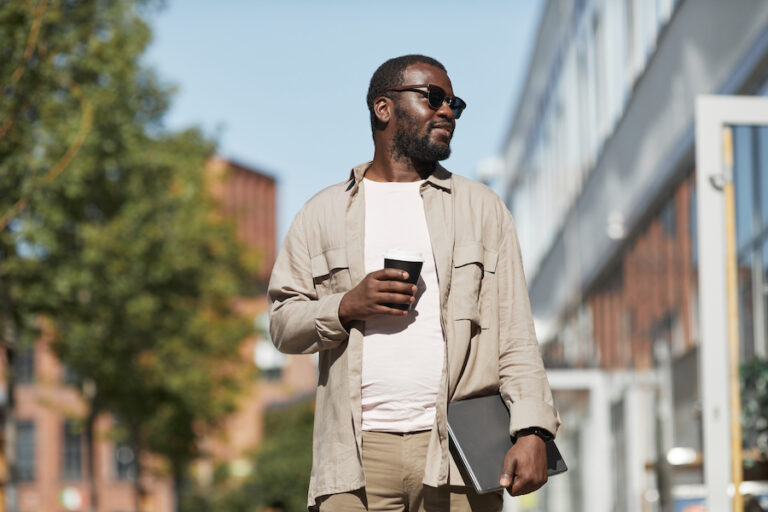 Portrait of black man wearing sunglasses outdoors while walking towards camera in San Diego