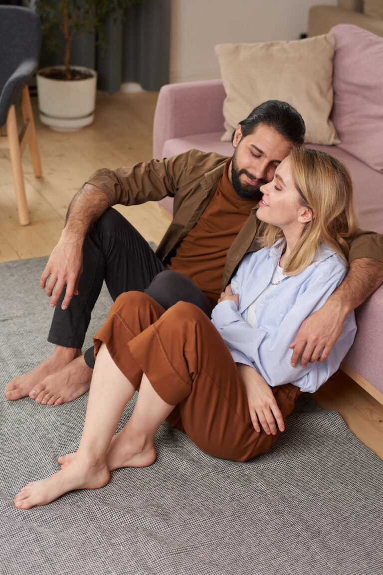 High angle shot of young man and woman in love spending time together at home sitting on floor in living room. Represents relationship after participating in online couples therapy in California with couples counselor Jordan Zipkin.