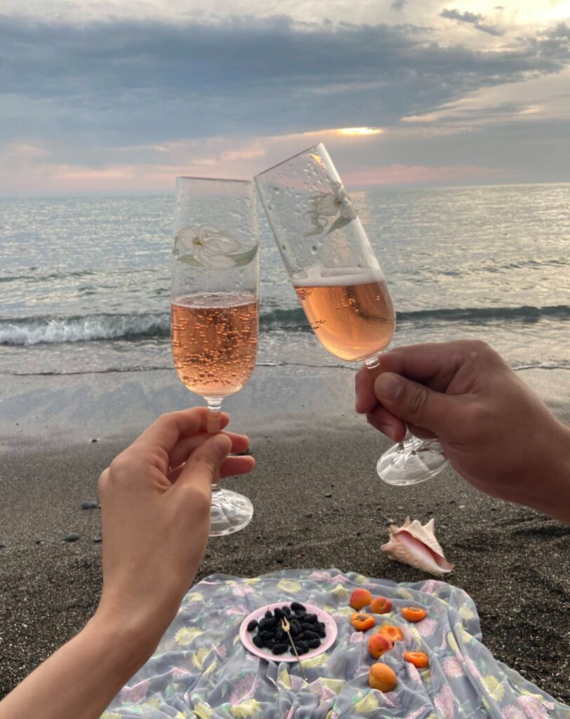 An image of two champagne glasses on a sandy beach. Amidst challenges this image is suggesting a hopeful date night to save a failing relationship. The scene encapsulates the couple's intent to rekindle romance and create cherished memories together.