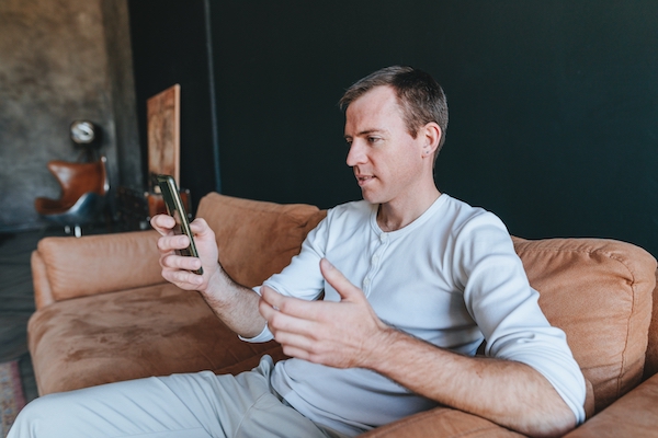 San Diego man using his smartphone to participate in an online therapy session to deal with his stress and lack of fulfillment in life.