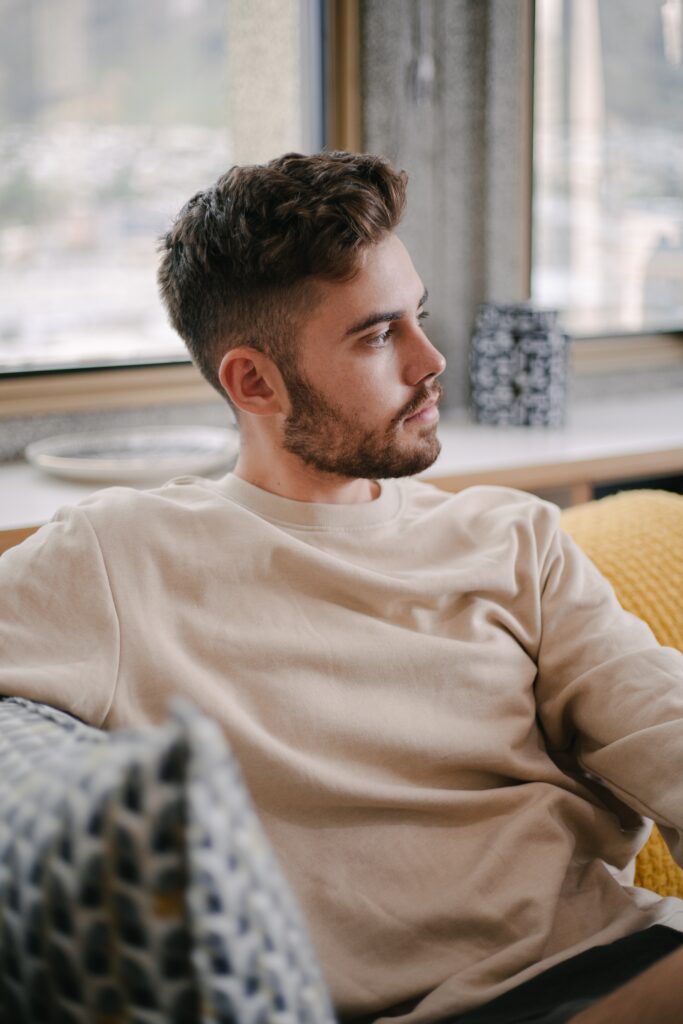 A man sitting on a couch, appearing deep in thought, illustrating the process of managing obsessive thinking and intense emotions