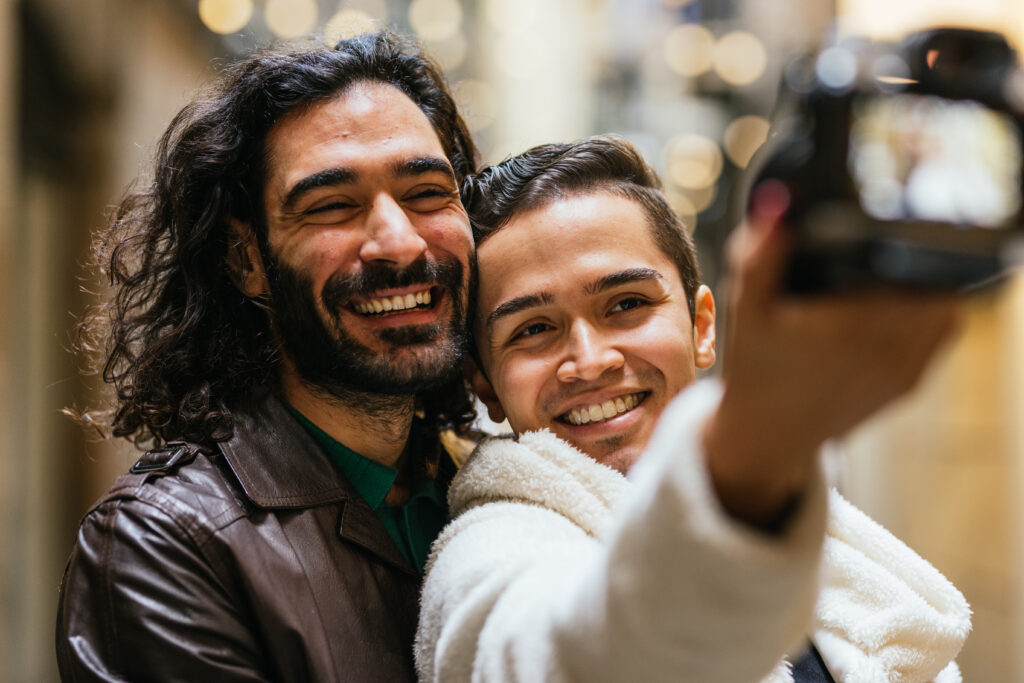 A gay couple smiles while taking a photo with a camera. This could represent the bonds cultiavted after creating boundaries. Learn more about the help an online therpaist in Oregon can offer by searching for online therapy in Portland, OR today. Search for anxitey help in San Diego today. 
