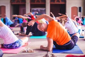 A man sits in a yoga class while stretching. Learn tips for stress managment in San Diego, CA by searching for a San Diego therapist for men. They can offer help in learning to cope with stress in San Diego, CA today.

