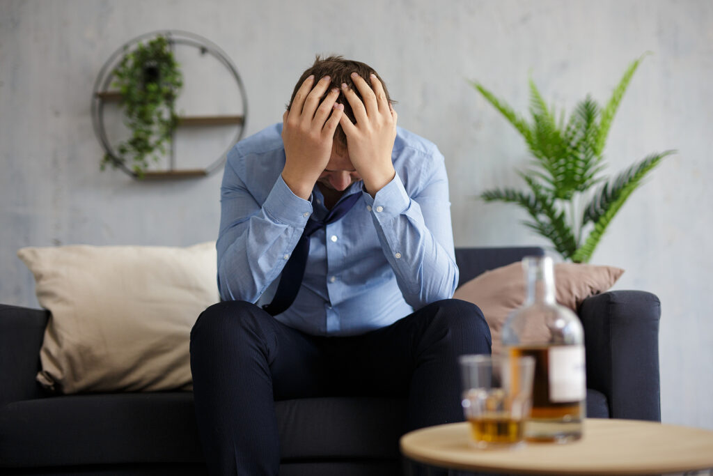 A man holds his head while sitting in front of liquor. Learn how to cope with stress in San Diego, CA and healthy coping skills. Learn more about the help an online therapist in Oregon can offer via online therapy for men in Portland, OR.
