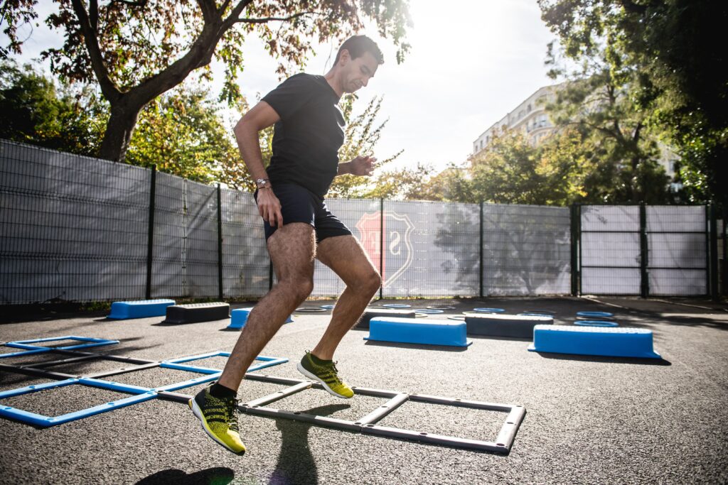 Man in Florida exercising on asphalt in a gym's yard, hopping between squares on the ground and using healthy coping mechanisms for stress like exercise to feel better.