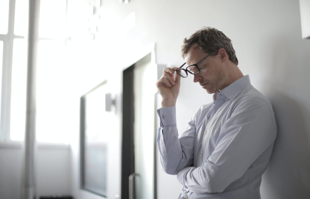 A man appears stressed while taking his glasses off of his face. Contact a San Diego counselor for help with addressing mental health issues in men. Search for online therapy in Oregon or contact a San Diego therapist for men to learn more. 