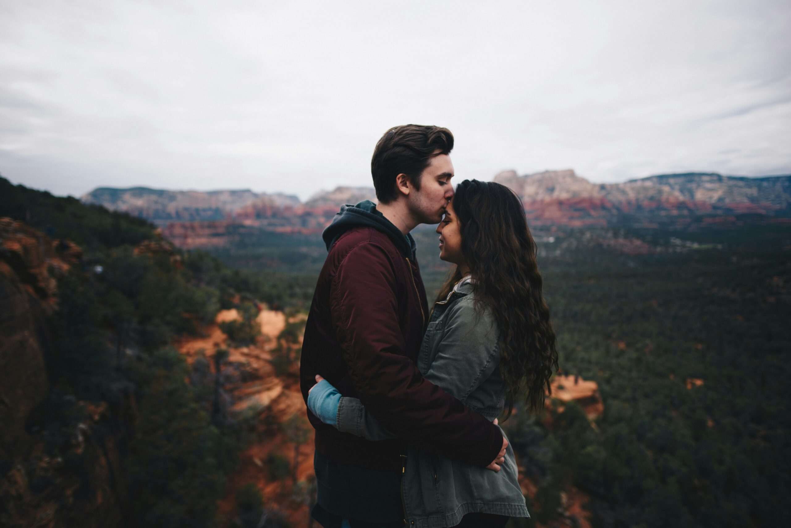 A photo of a couple standing face to face on a mountaintop beautifully captures the essence of relationship happiness and stability through the help of therapy in California