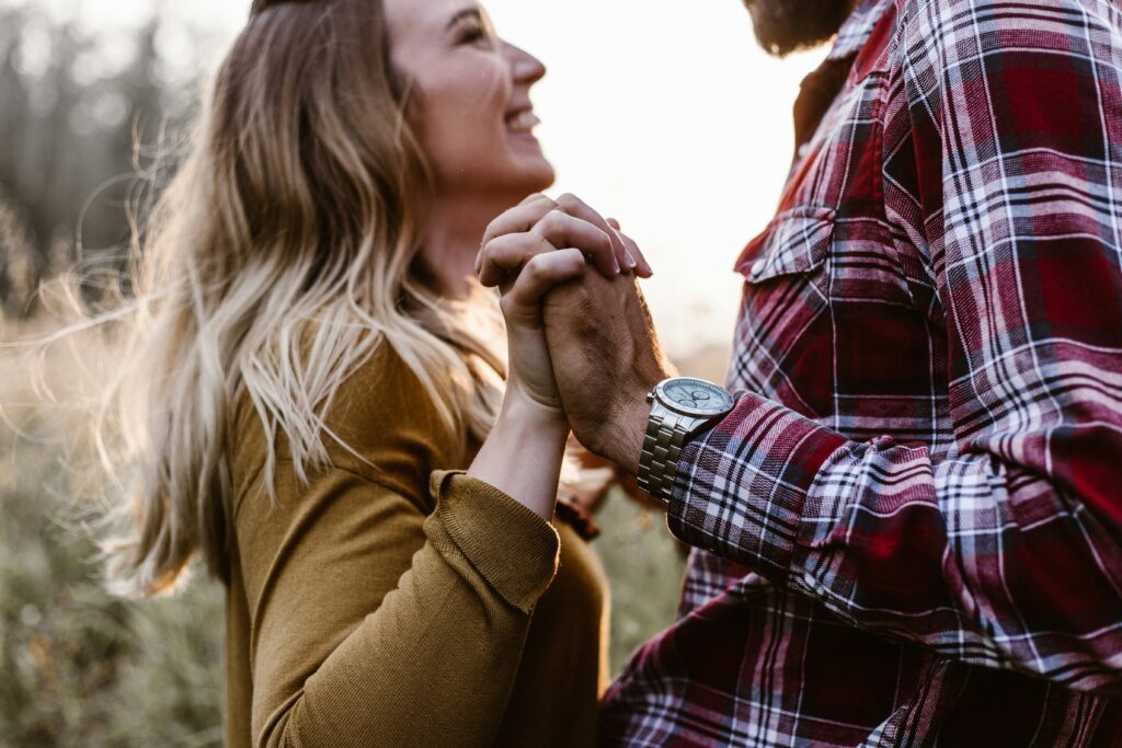 A close-up photo of a couple holding hands illustrating the nature of relationship happiness and stability. 