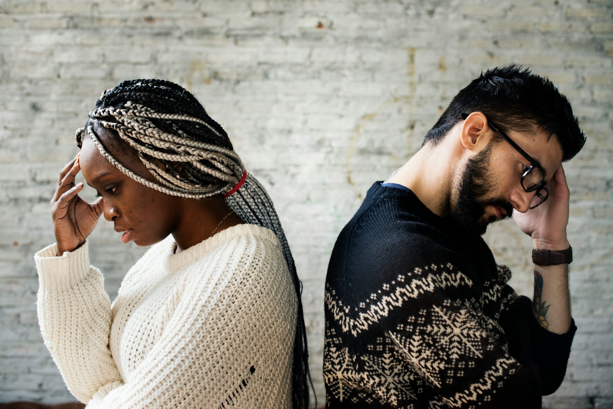 A distressed couple sitting back-to-back, representing the strain caused by unbridled self-expression in relationships and the need for healthier communication strategies.