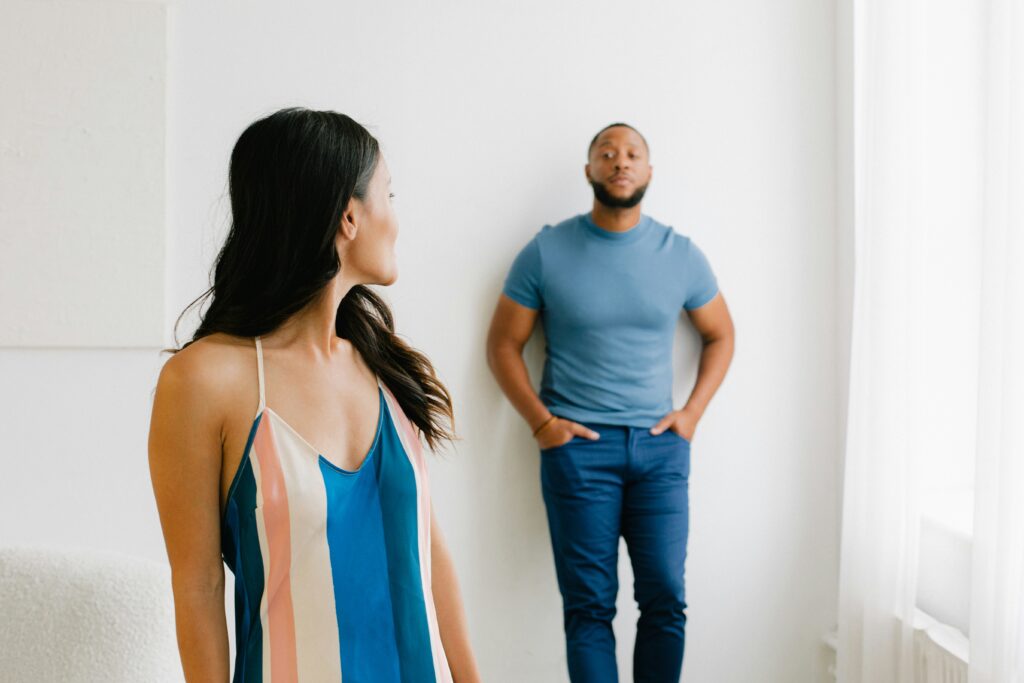 A couple standing apart in a strained confrontation, representing the challenges of overcoming retaliation or revenge in relationship dynamics.