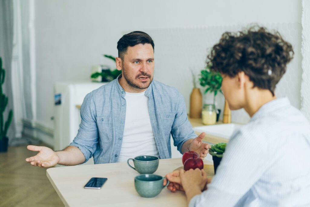 A couple in a serious conversation at home, illustrating unbridled self-expression and communication challenges often addressed by a relationship therapist.