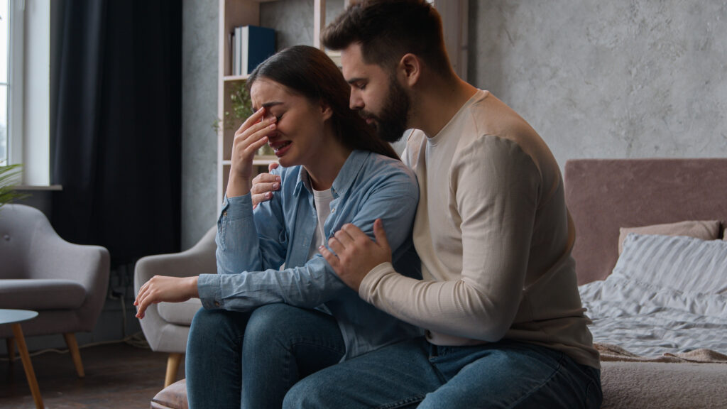 Man supporting distressed partner, portraying the quiet pressure of being “the strong one” and the need to share emotional responsibilities.