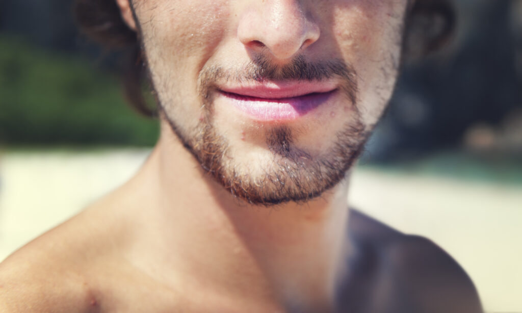 Young man smiling confidently outdoors, representing positive outcomes of men's mental health care and San Diego anxiety therapy.