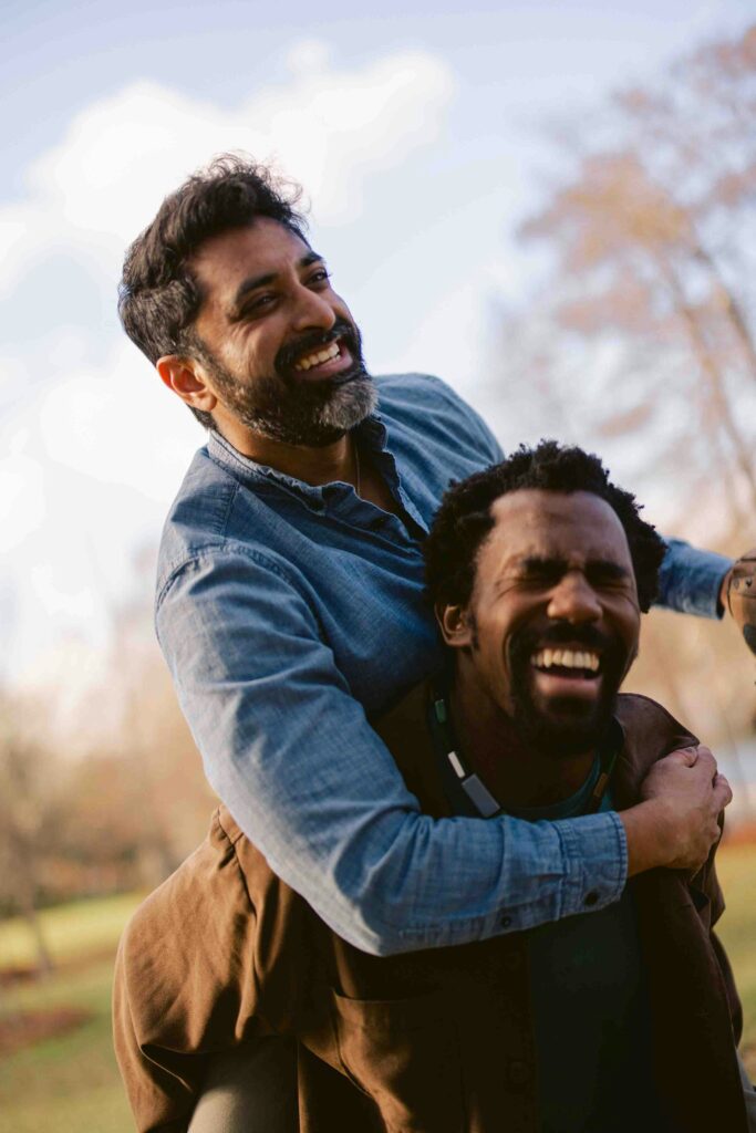 Two men sharing a joyful moment together, illustrating the positive impact of therapy. San Diego therapy for men helps break the stigma surrounding men's mental health and encourages emotional openness.