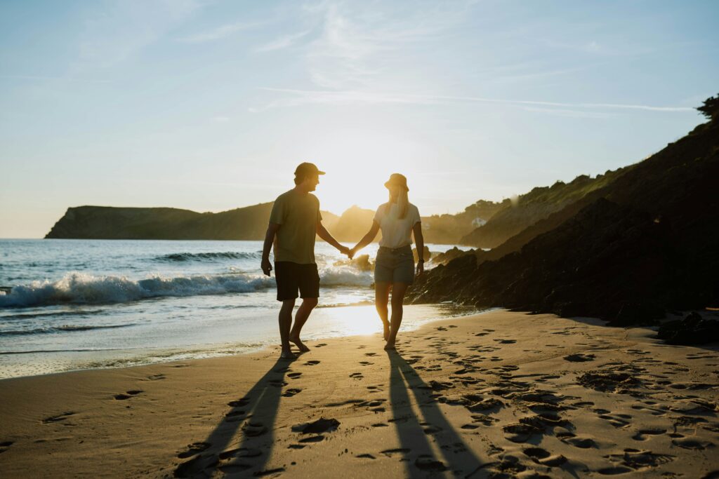 A couple walking hand in hand along the beach at sunset, representing healing, forgiveness, and relationship repair achieved through couples therapy in California and learning how to apologize effectively.