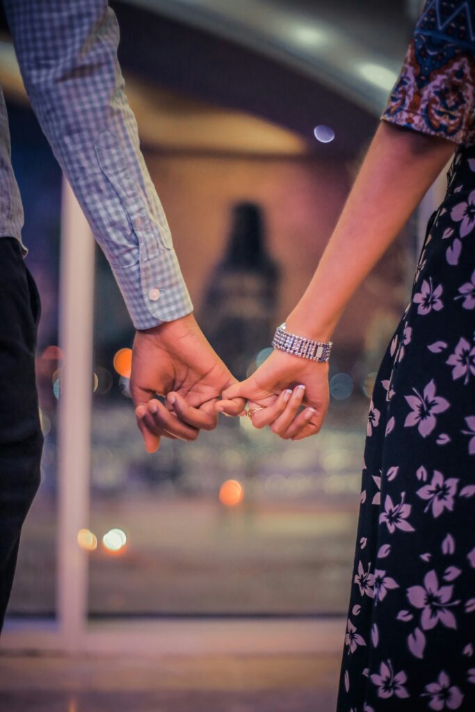A couple holding hands and linking fingers in a gentle moment of connection, symbolizing relationship repair and emotional closeness after learning how to apologize in couples therapy in California.