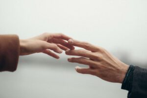 Close-up of hands reaching toward each other, symbolizing effort toward reconnection in work with a couples therapist in San Diego, CA.