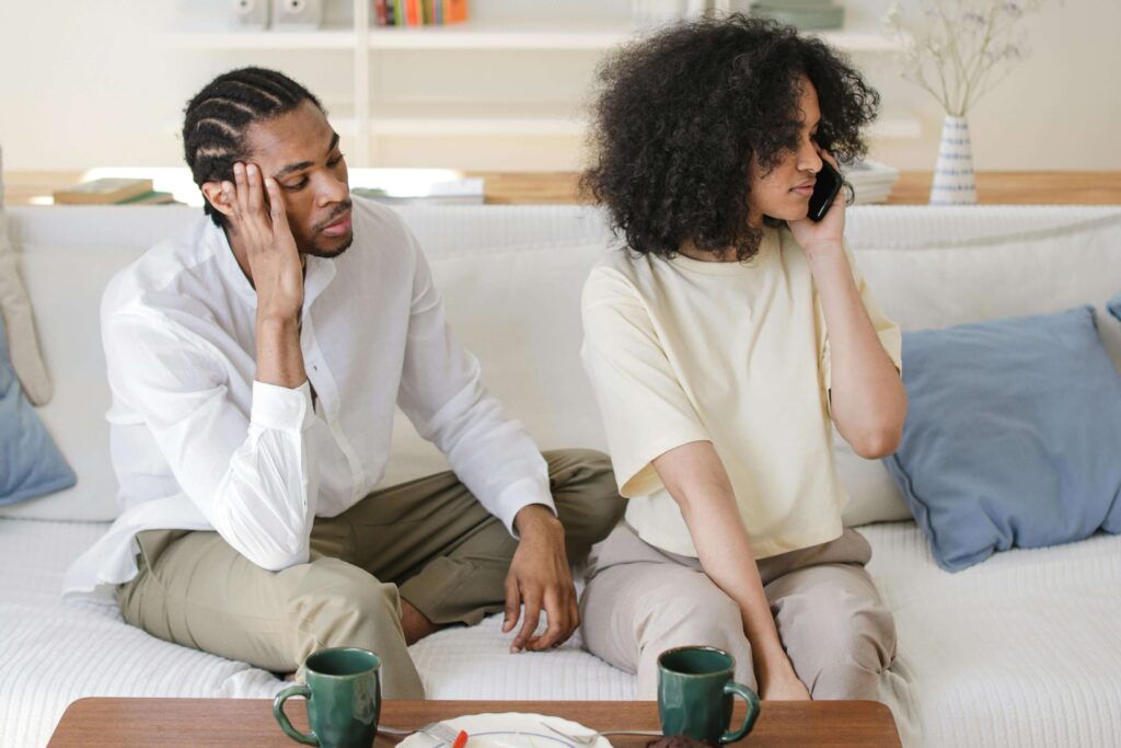 Distracted Togetherness - couples therapist san diego ca - couples therapy san diego ca - couples therapy for conflict san diego ca - mission valley - la - san francisco - california Couple sitting on a couch together, with the woman turned away and focused on her phone, illustrating disconnection explored with a couples therapist in San Diego, CA.