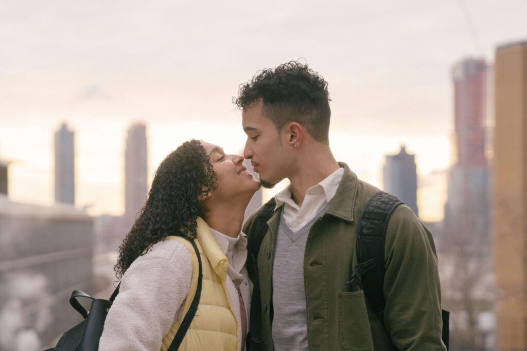 Happy couple leaning in for a kiss, symbolizing closeness and understanding supported through couples therapy for defensiveness in San Diego, CA.