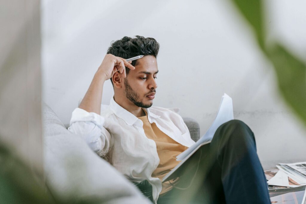 Man journaling while sitting on a couch, illustrating self-awareness and communication work supported in couples therapy for emotional avoidance in San Diego, CA.