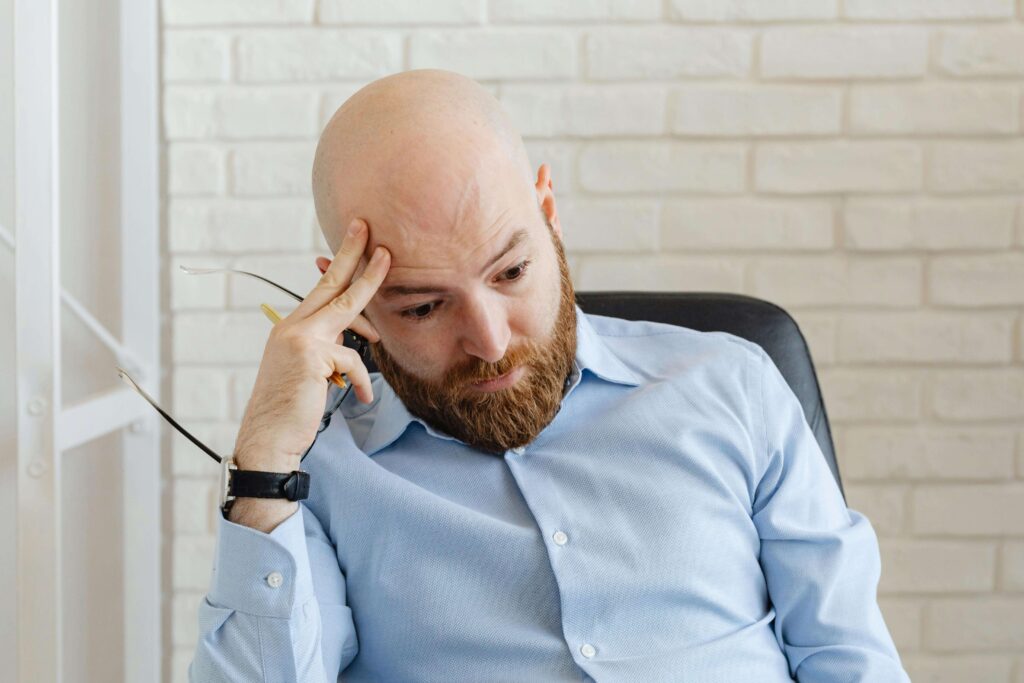 Man taking off his glasses and looking down after forgetting something, representing attention and follow-through challenges addressed in couples therapy for ADHD in San Diego, CA.