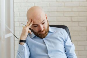 Man taking off his glasses and looking down after forgetting something, representing attention and follow-through challenges addressed in couples therapy for ADHD in San Diego, CA.