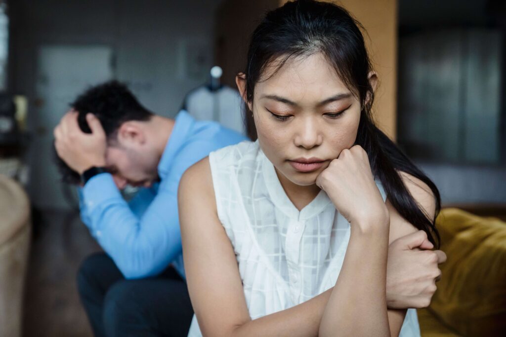 Close-up of a couple looking stressed, with the woman looking down thoughtfully, representing concerns explored in relationship counseling in San Diego, CA.