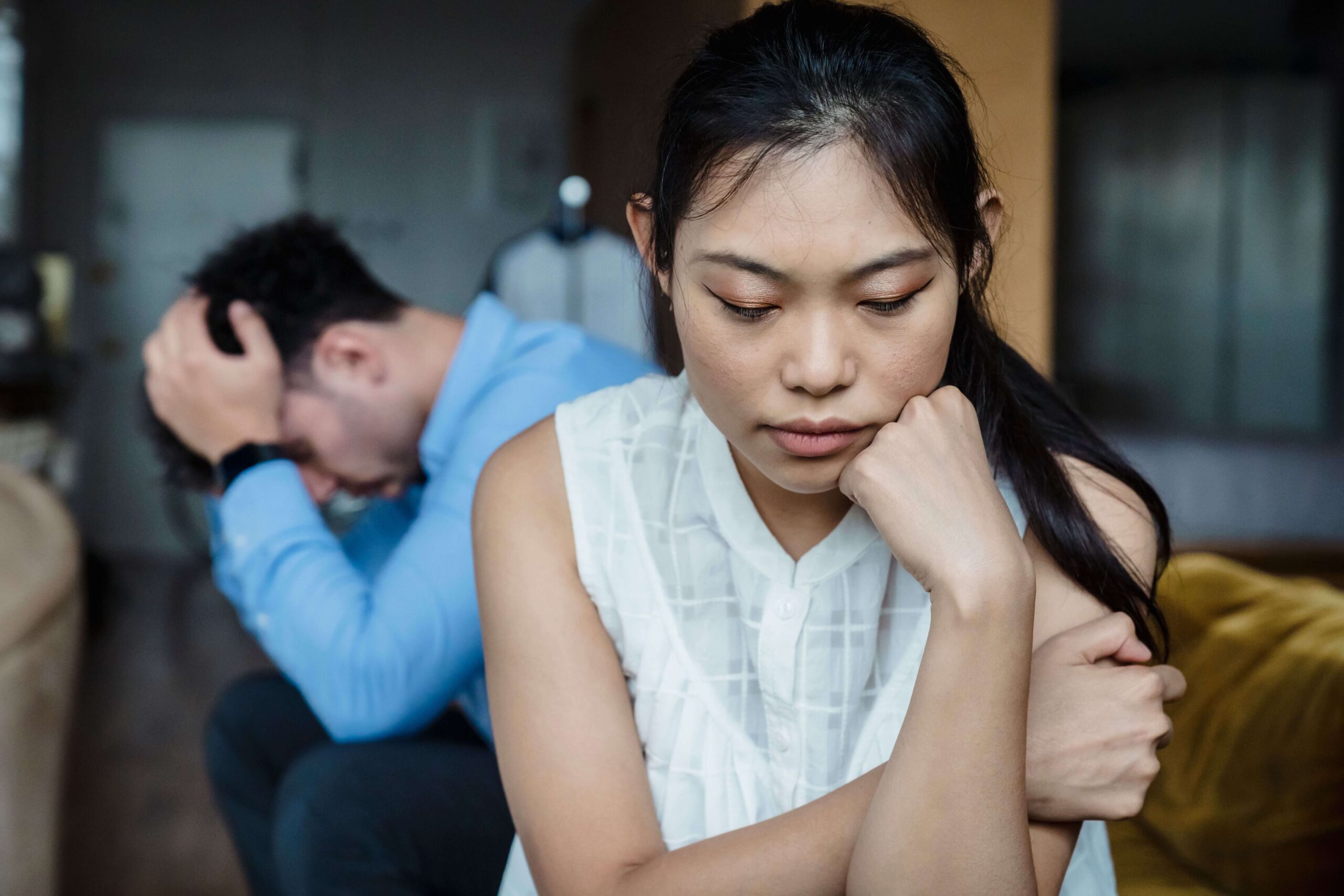 Close-up of a couple looking stressed, with the woman looking down thoughtfully, representing concerns explored in relationship counseling in San Diego, CA.