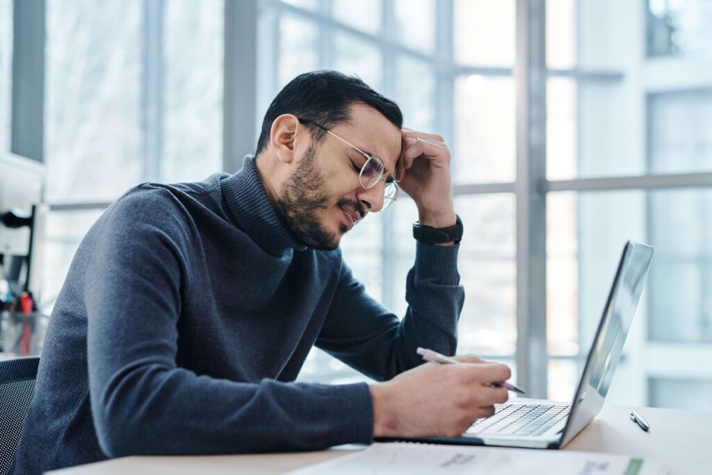 Man appearing stressed at work, illustrating how professional demands can contribute to relationship tension addressed through couples therapy in San Diego, CA.