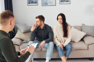 Couple sitting beside each other as a counselor takes notes, illustrating infidelity counseling in San Diego.