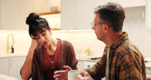 Woman resting her head on her hand as her partner speaks, illustrating a difficult relationship conversation.