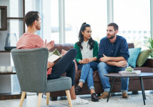 Couple speaking with a therapist in a bright office, illustrating Gottman couples therapy in San Diego.